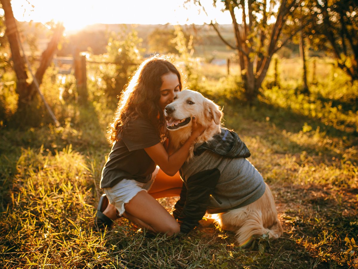 Een vrouw omhelst haar hond buiten in het avondlicht